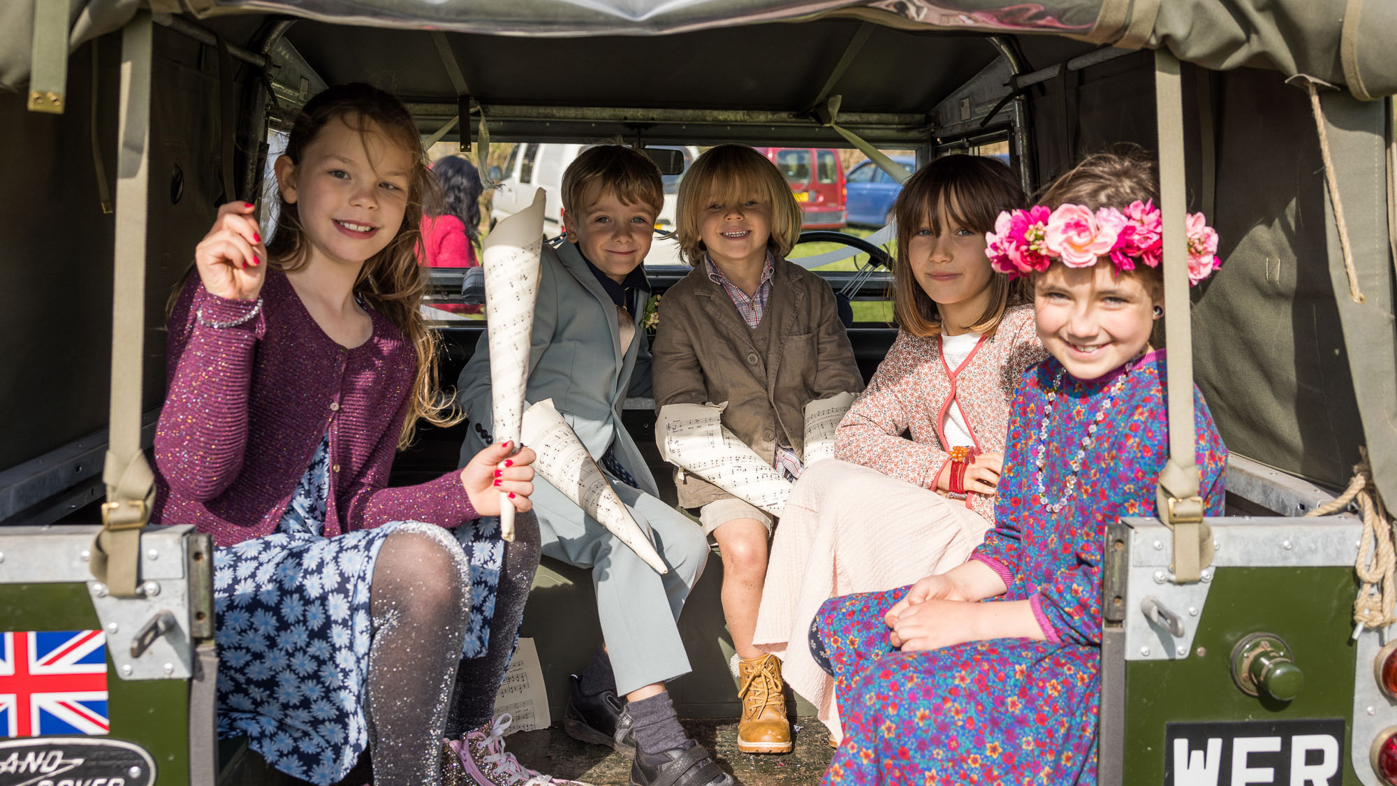 Flower girls seating inside a classic Land Rover.