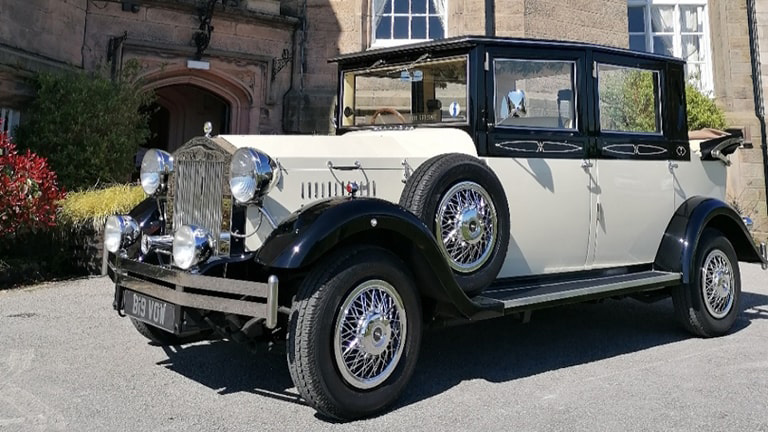 Ivory Imperial wedding car with Black wheel arches and roof and a spare wheel mounted on the side of the vehicle