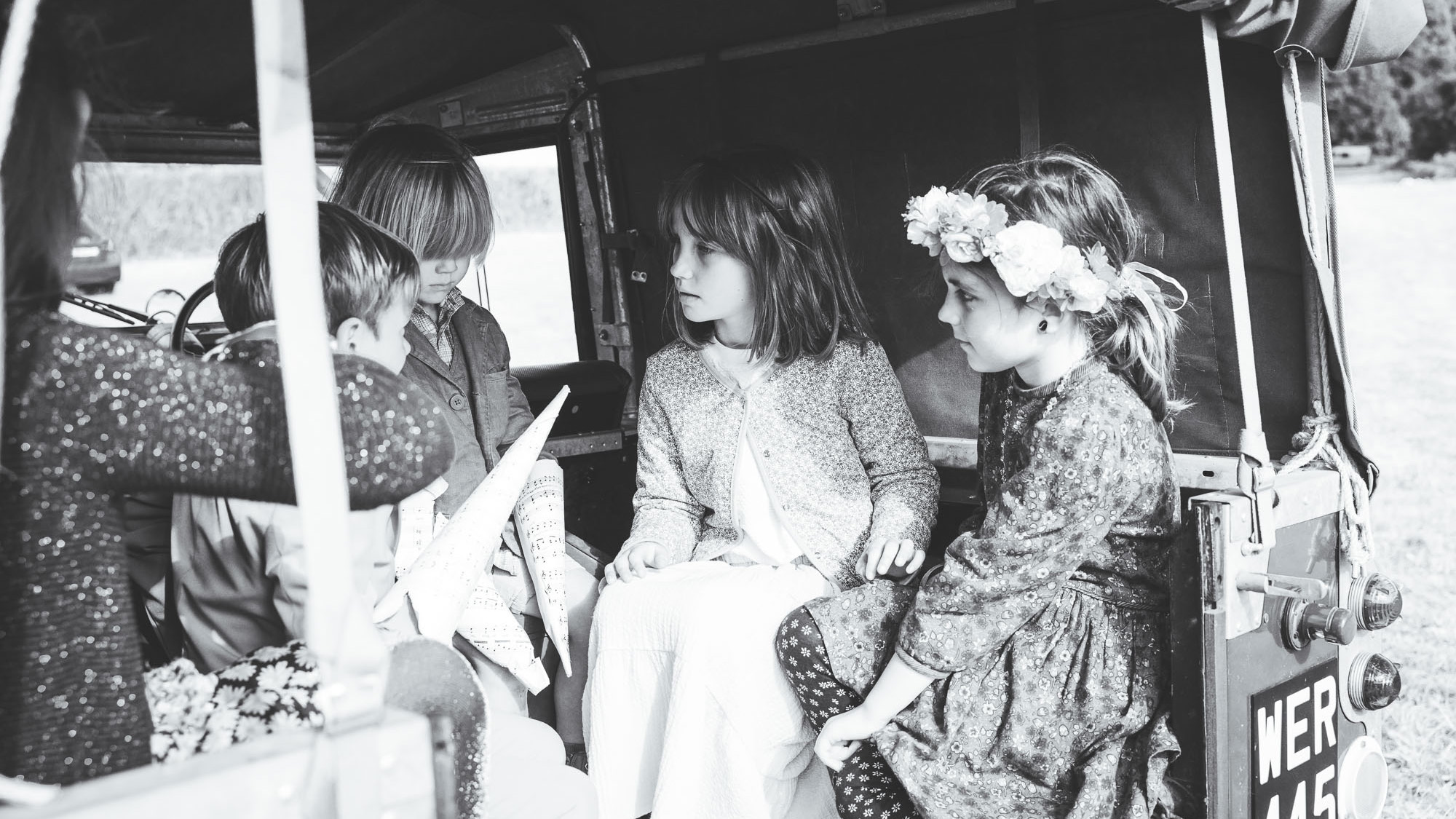 Black and White photo of wedding guests seating at the rear of a classic Landrover