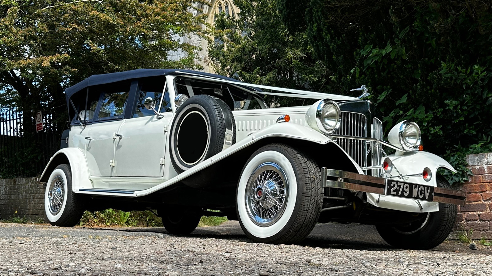 right side view of Beauford convertible showing the white wall tires, wired spokes wheels and spare wheel mounted on the side of the vehicle.