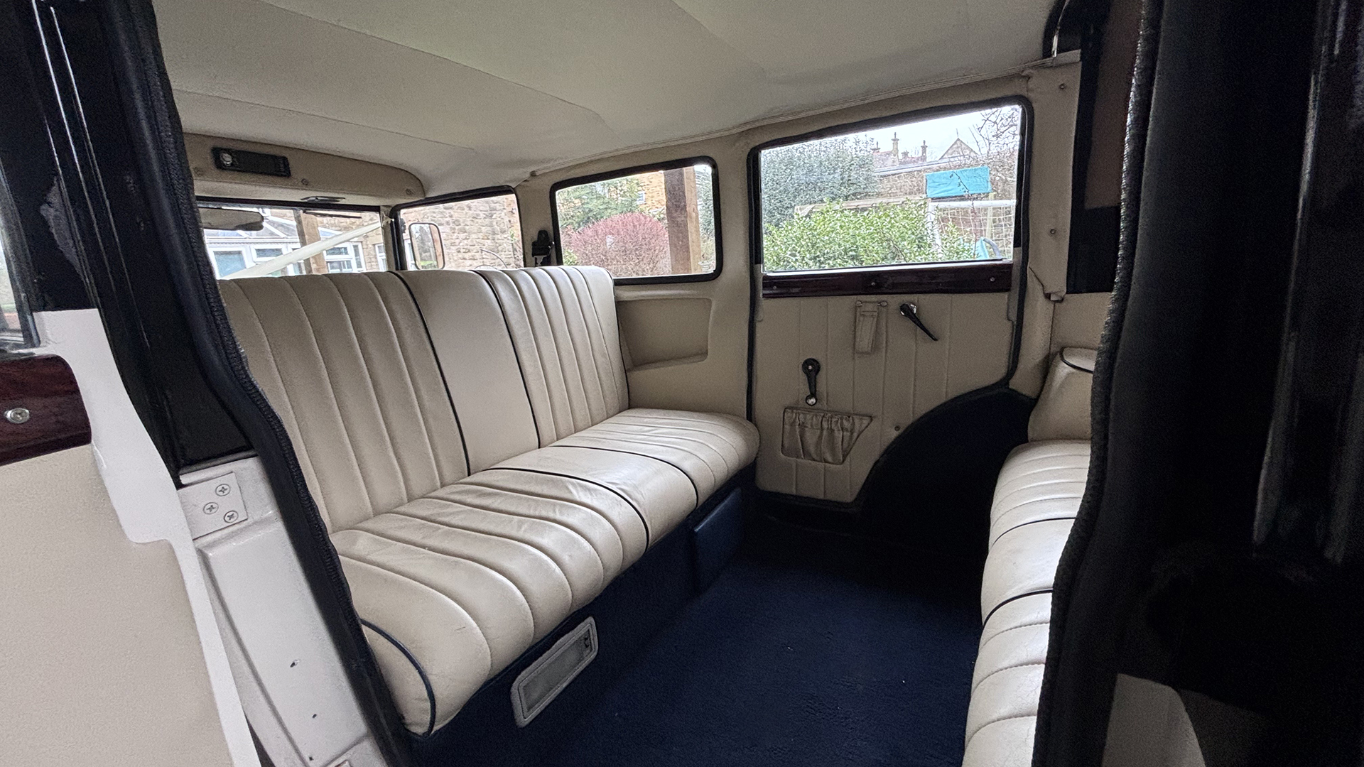 rear interior space inside Bramwith wedding car with royal blue carpet and cream leather bench seats