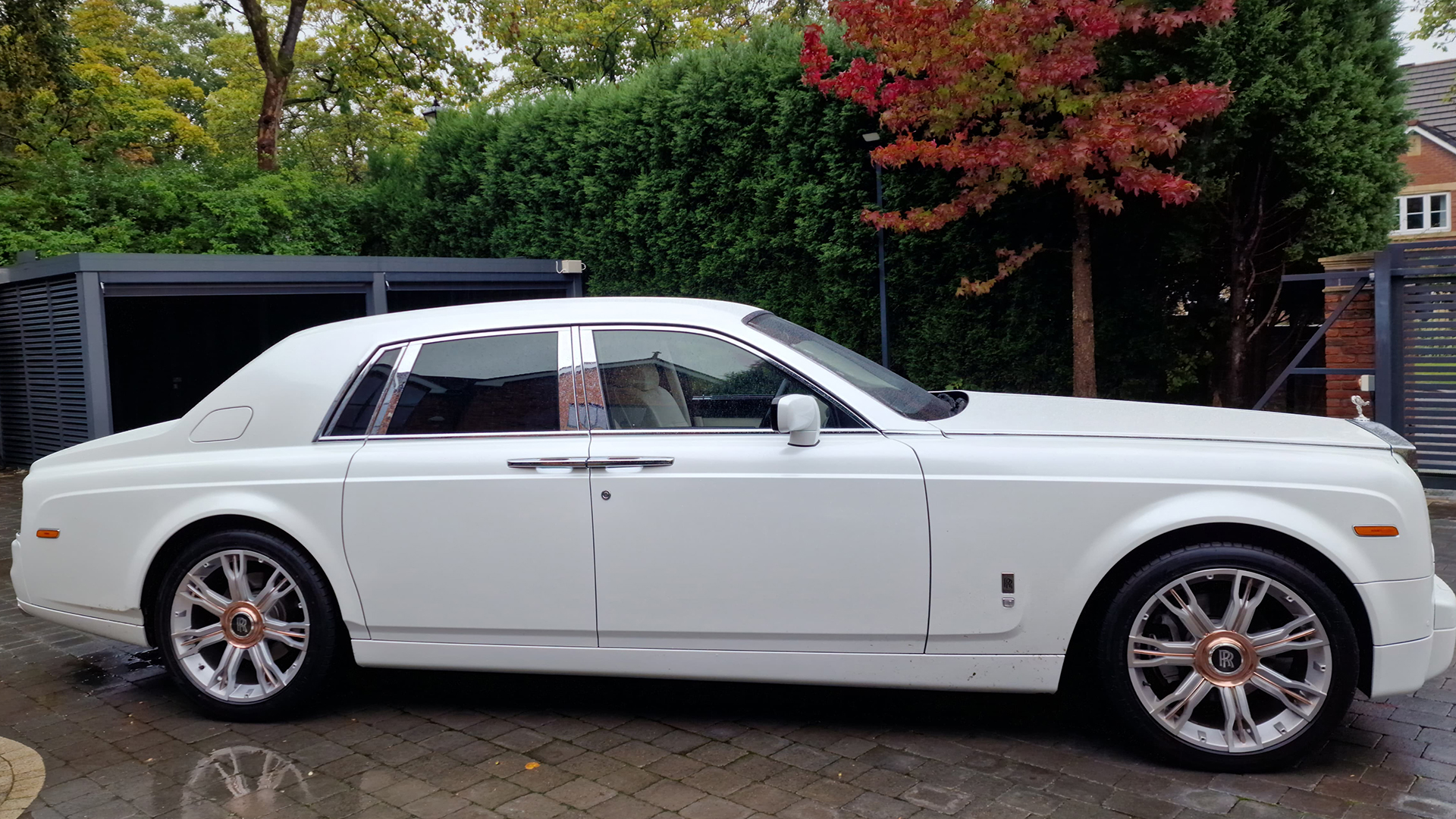 Right side view of a 4-door Rolls-Royce Phantom with large chrome alloy wheels with rose-gold centre caps