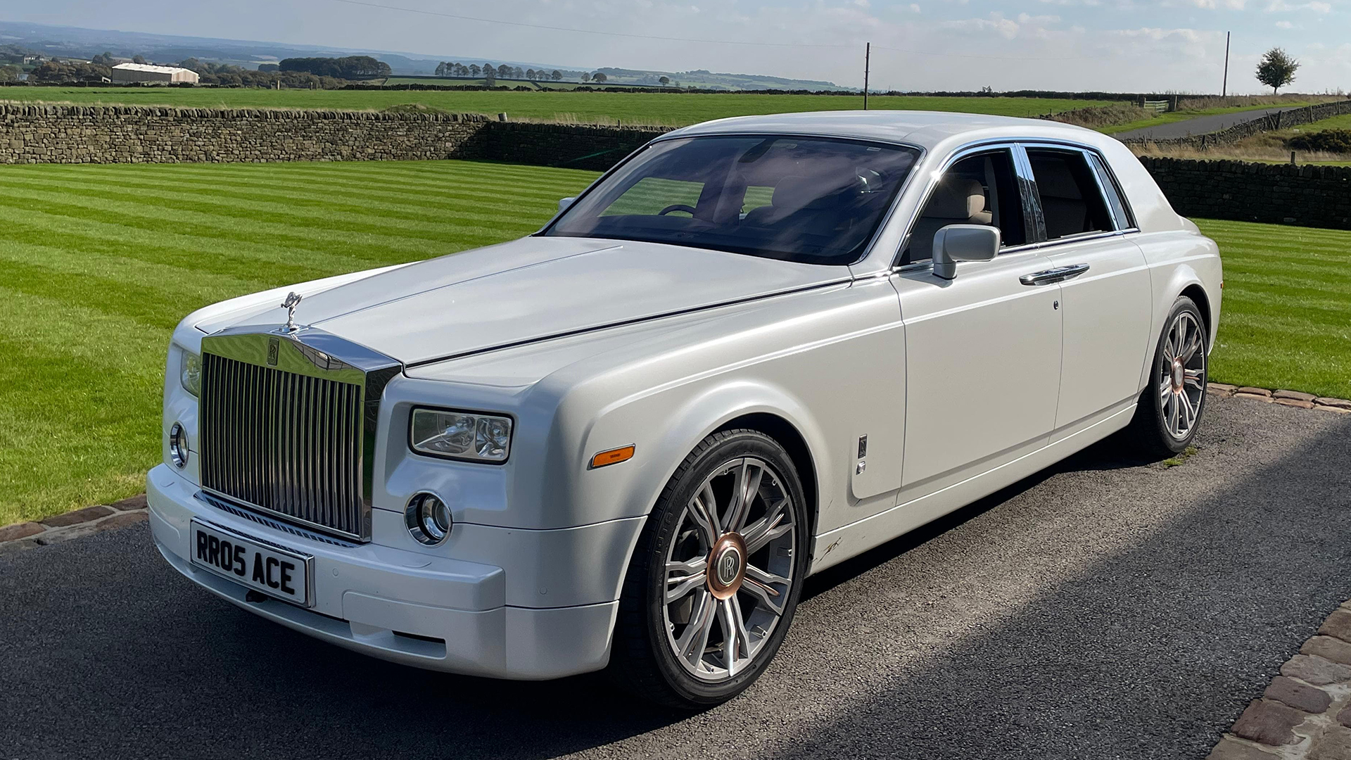 White Rolls-Royce Phantom with large alloy wheels and chrome front grill