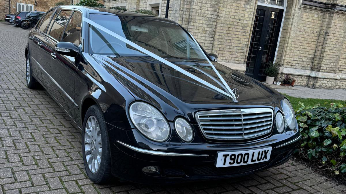 Front view of Stretched Mercedes Limousine with V-shape white ribbons across its bonnet.