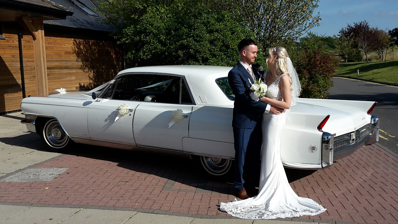 Bride and Groom holding each others with a classic white Cadillac in the background