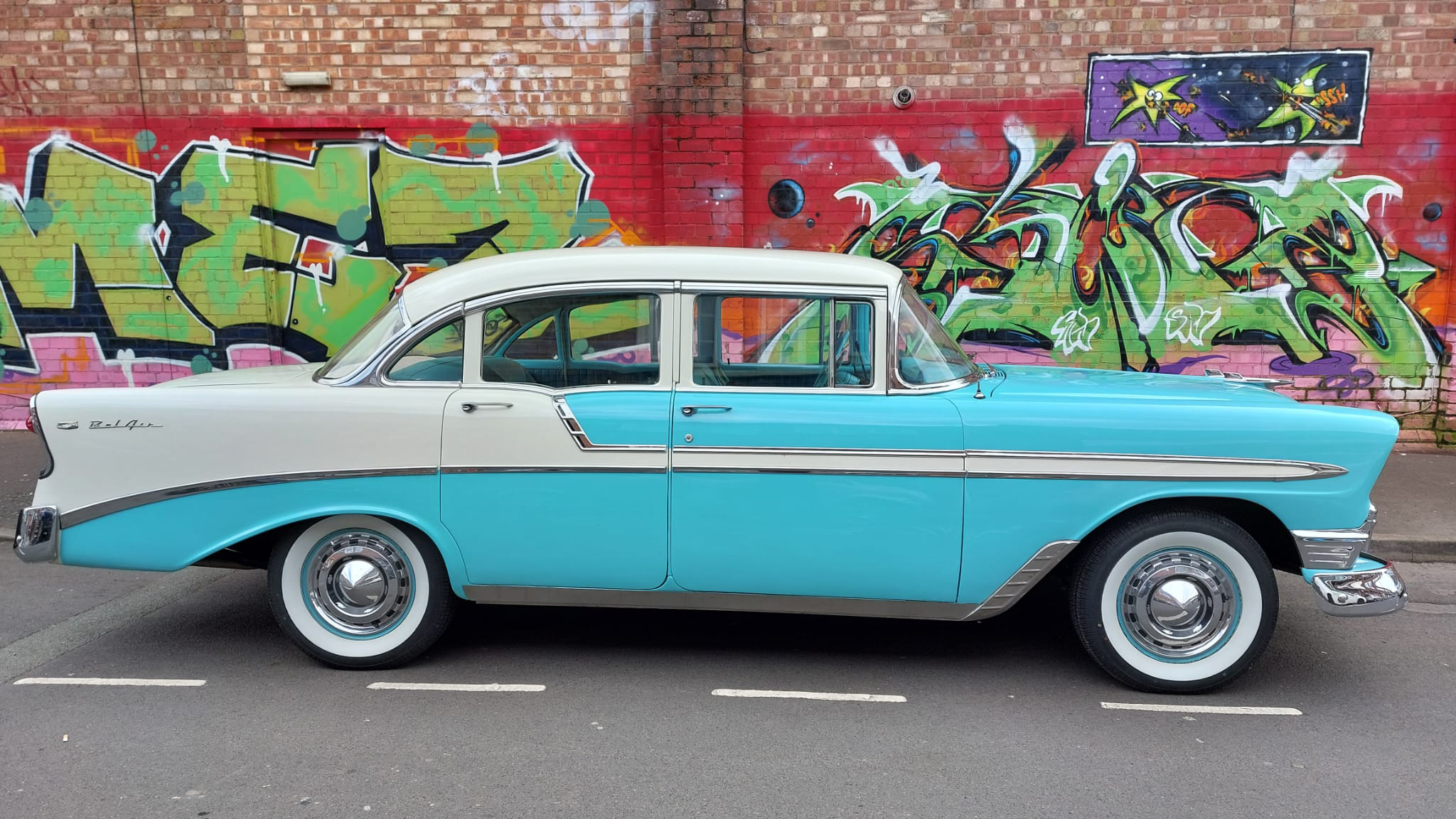 American Chevrolet BelAir right side view with artwork painted wall in the background