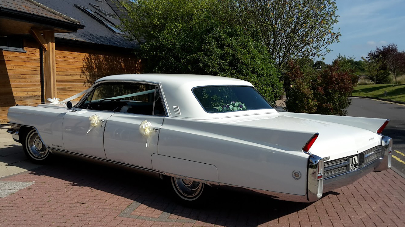 Rear left view of a Cadillac dressed with wedding ribbons and bows