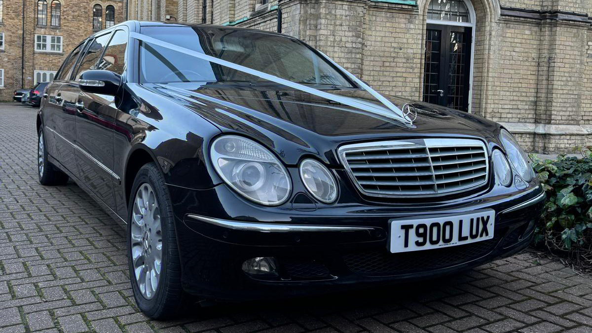 Front view of a black Mercedes Limousine decorated with white ribbons