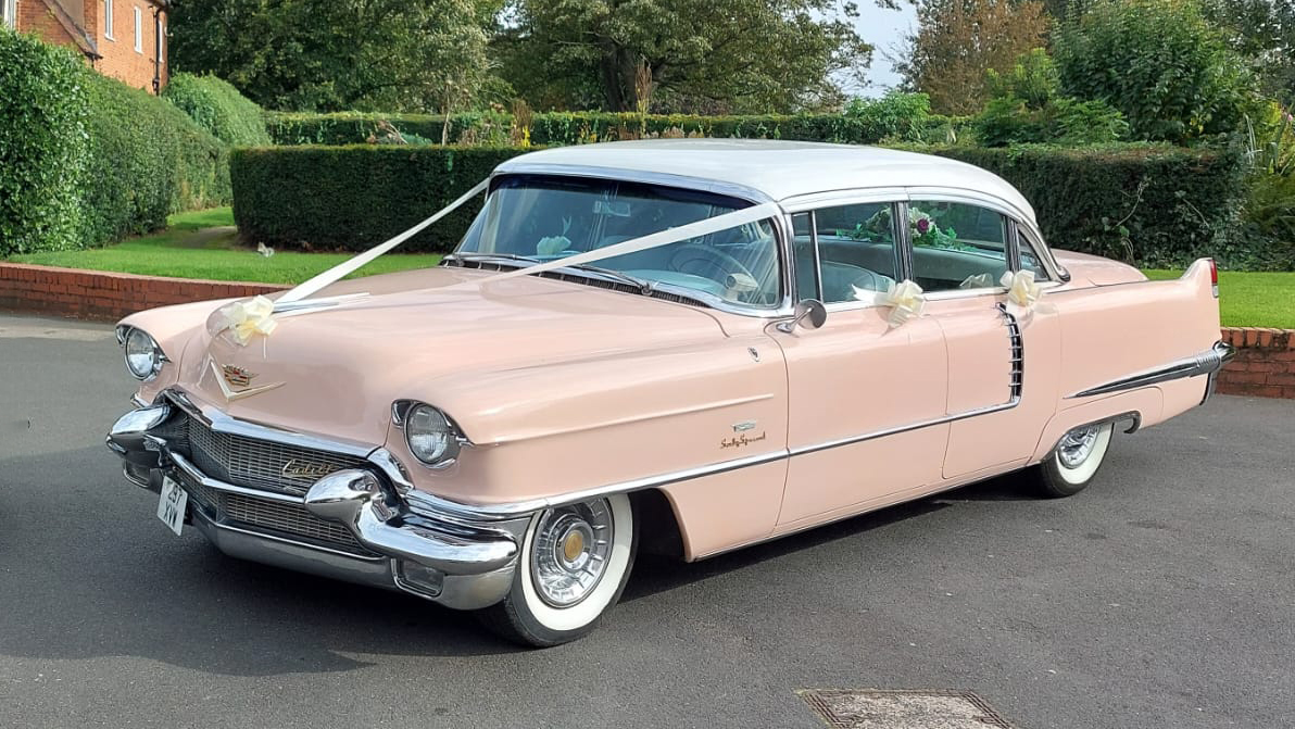 Classic Pink American Cadillac Fleetwood decorated with white wedding ribbons and bows