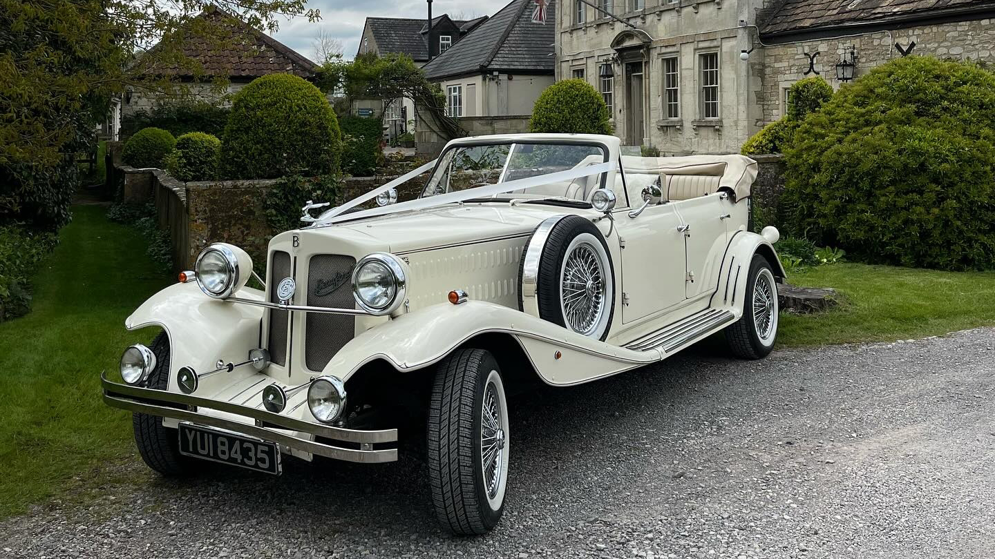 Vintage Beauford with convertible roof open dressed with Ivory ribbons parked in front of a church in Bristol