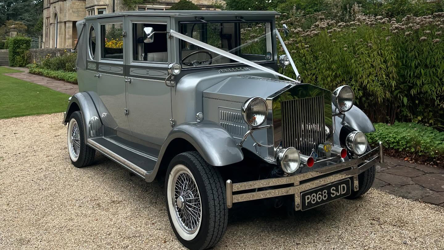 White wedding ribbons on a silver Imperial wedding car with chrome front bumper and grill.