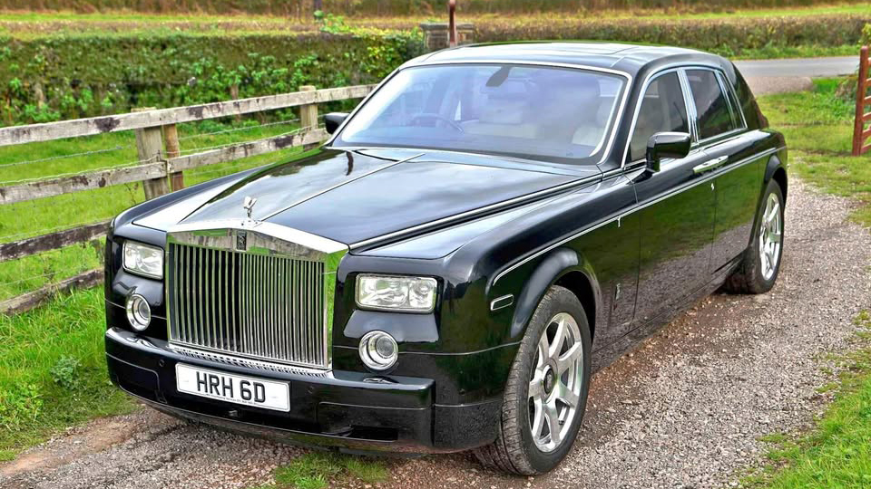 Black Rolls-Royce Phantom with large iconic chrome grill and tinted privacy windows at the rear