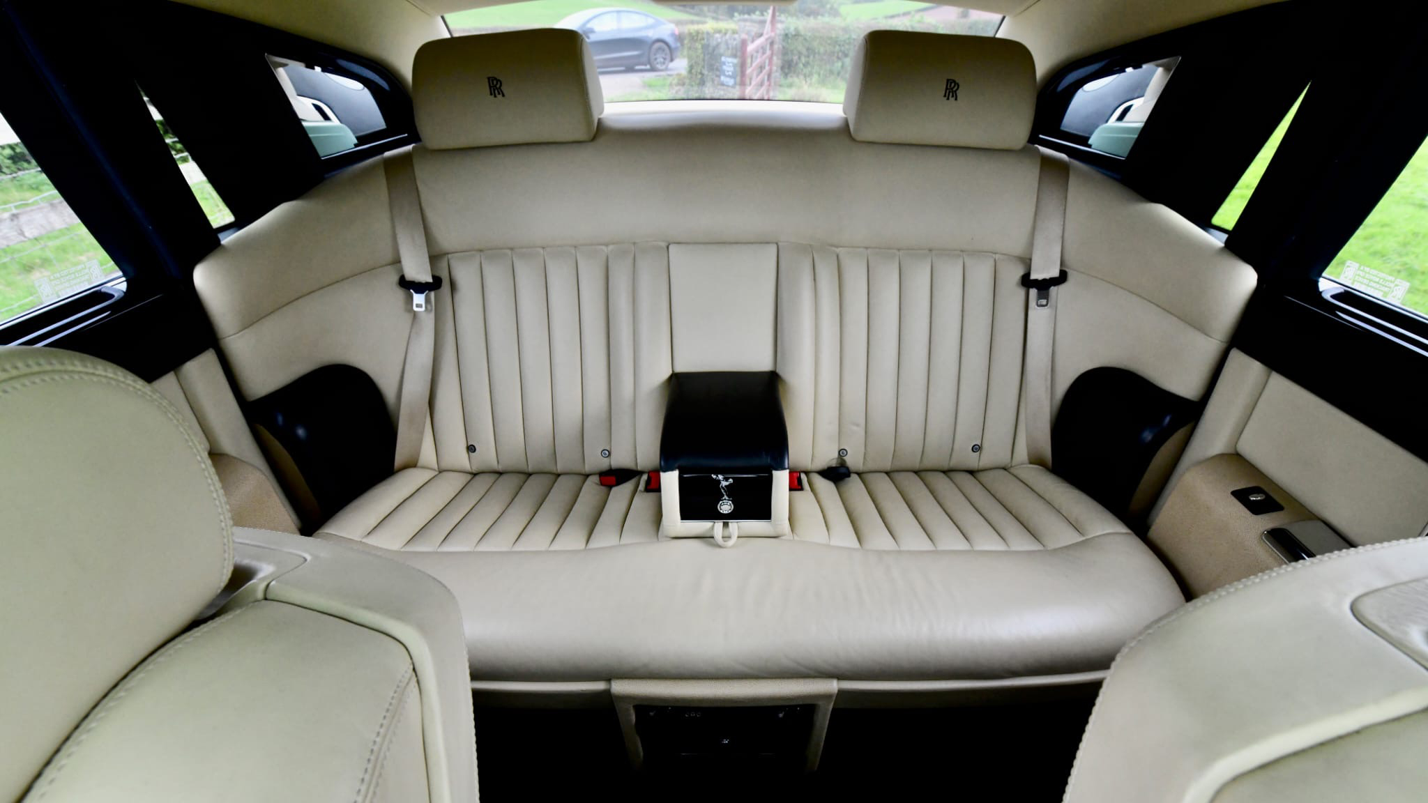 Rear seat inside Rolls-Royce Phantom with cream leather and black armrest in the middle