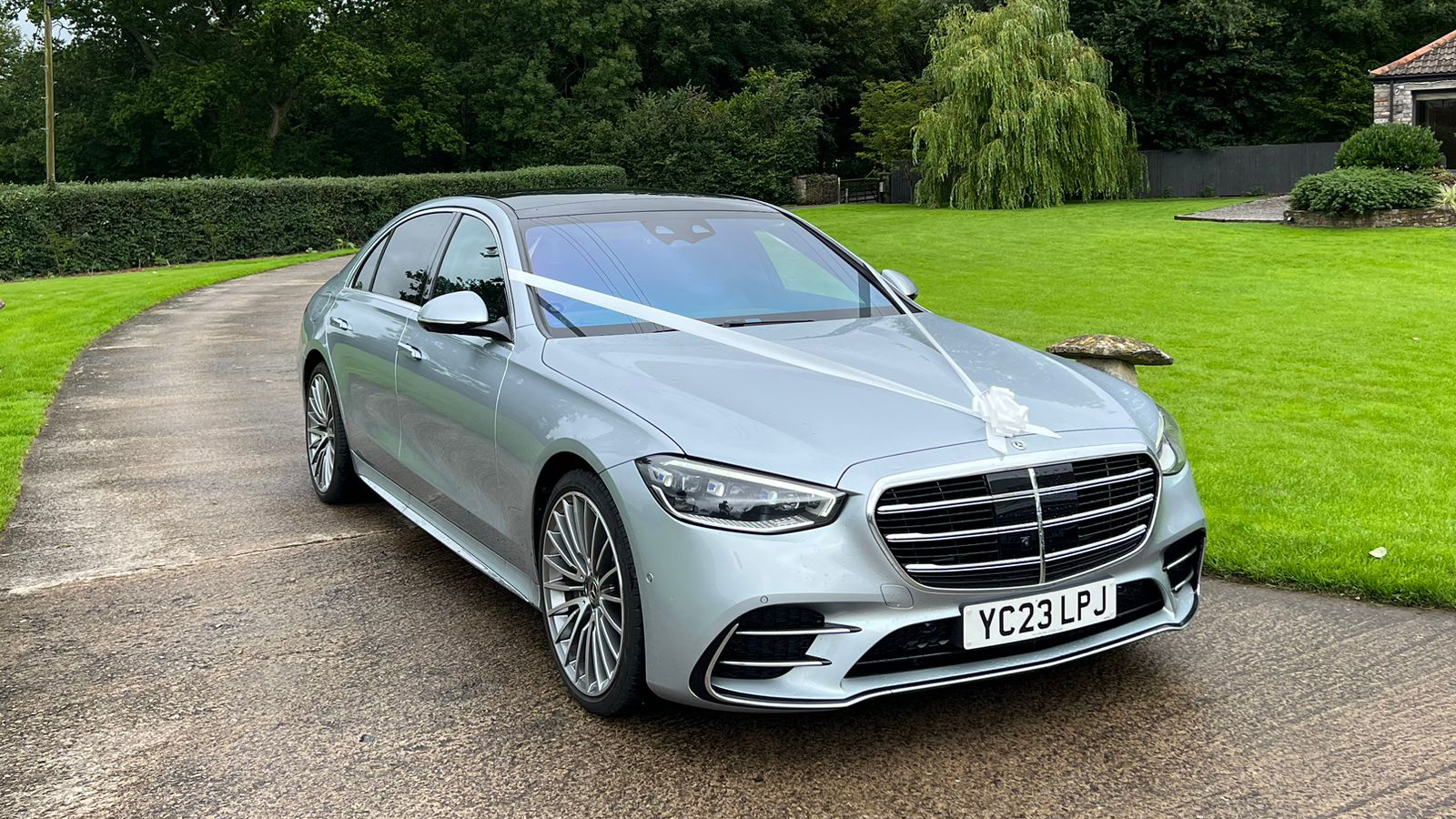 Silver Mercedes decorated with white wedding ribbons and bows