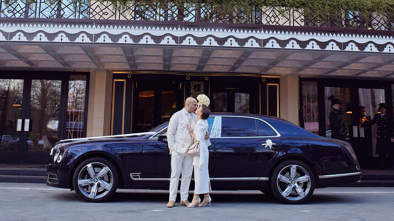 Bride and Groom kissing in front of a Blue Bentley parked outside the Dorchester hotel in London