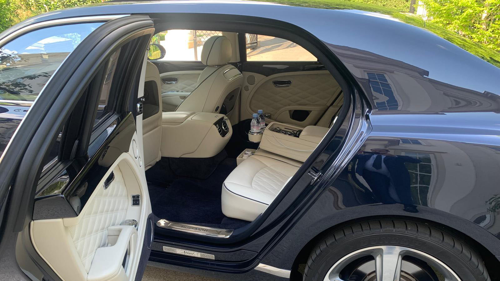 Rear left passenger door open showing a cream leather interior, blue carpet and plenty of legroom in a Bentley Mulsanne