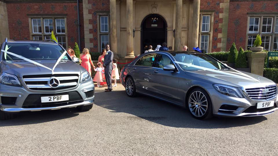 Two matching silver Mercedes GSL and S-Class both decorated with identical white ribbons parked in front of wedding venue in Cheshire