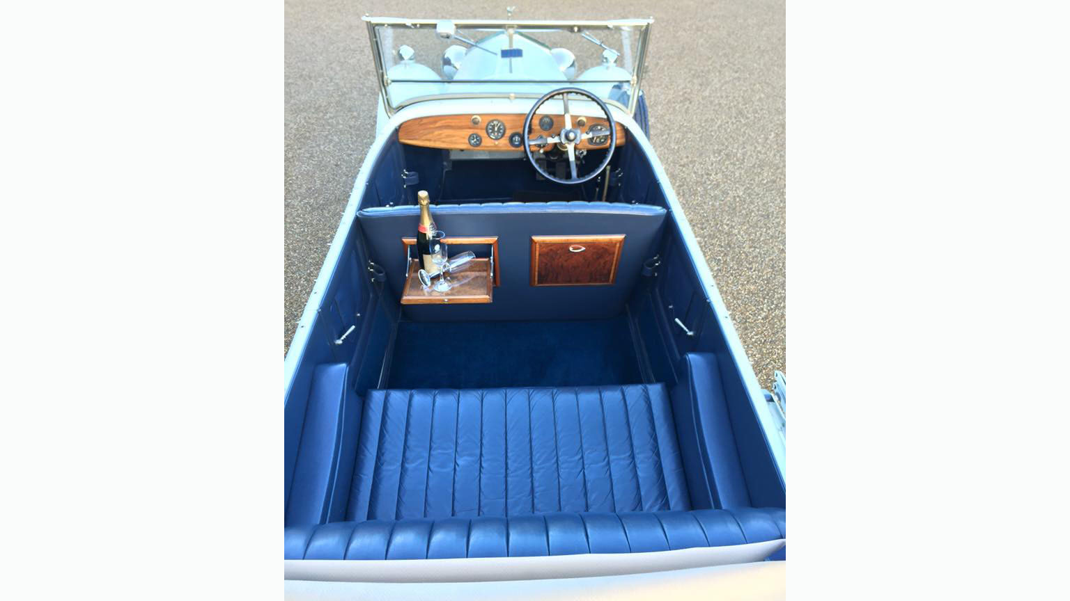 Aerial view of a vintage Rolls-Royce with convertible roof open showing matching blue seats, carpet and door cards.