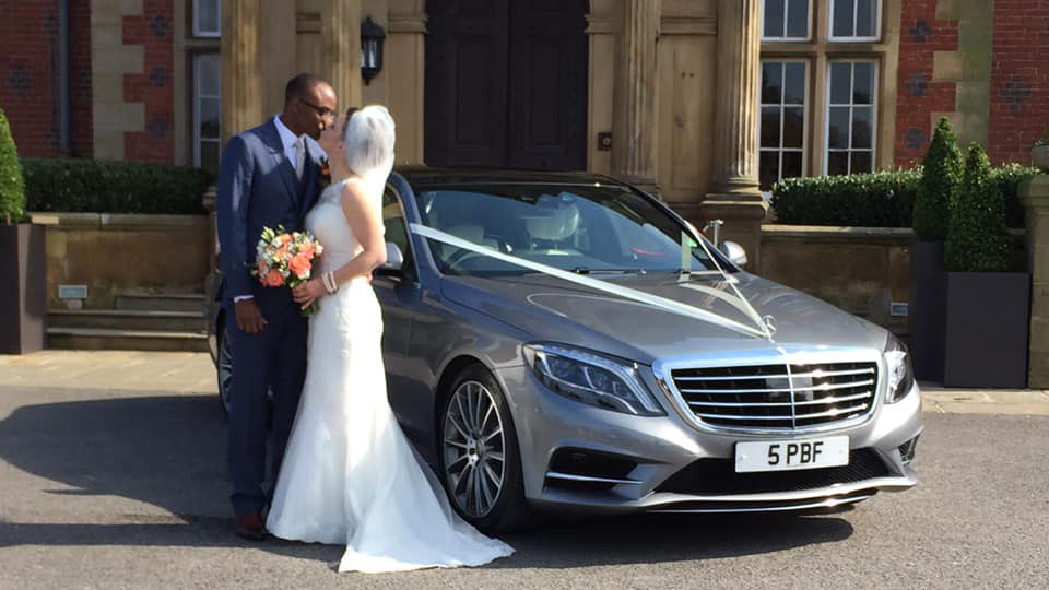 Bride and Groom holding each others in front of a silver Mercedes S-class