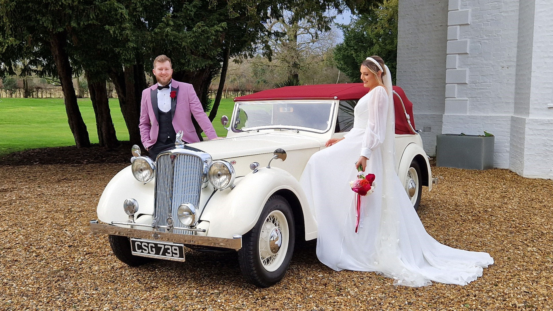 Bride and Groom standing on either side of a vintage Rover