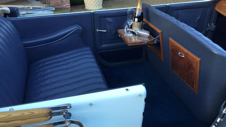 rear interior in vintage Rolls-Royce with matching blue seats and carpet,