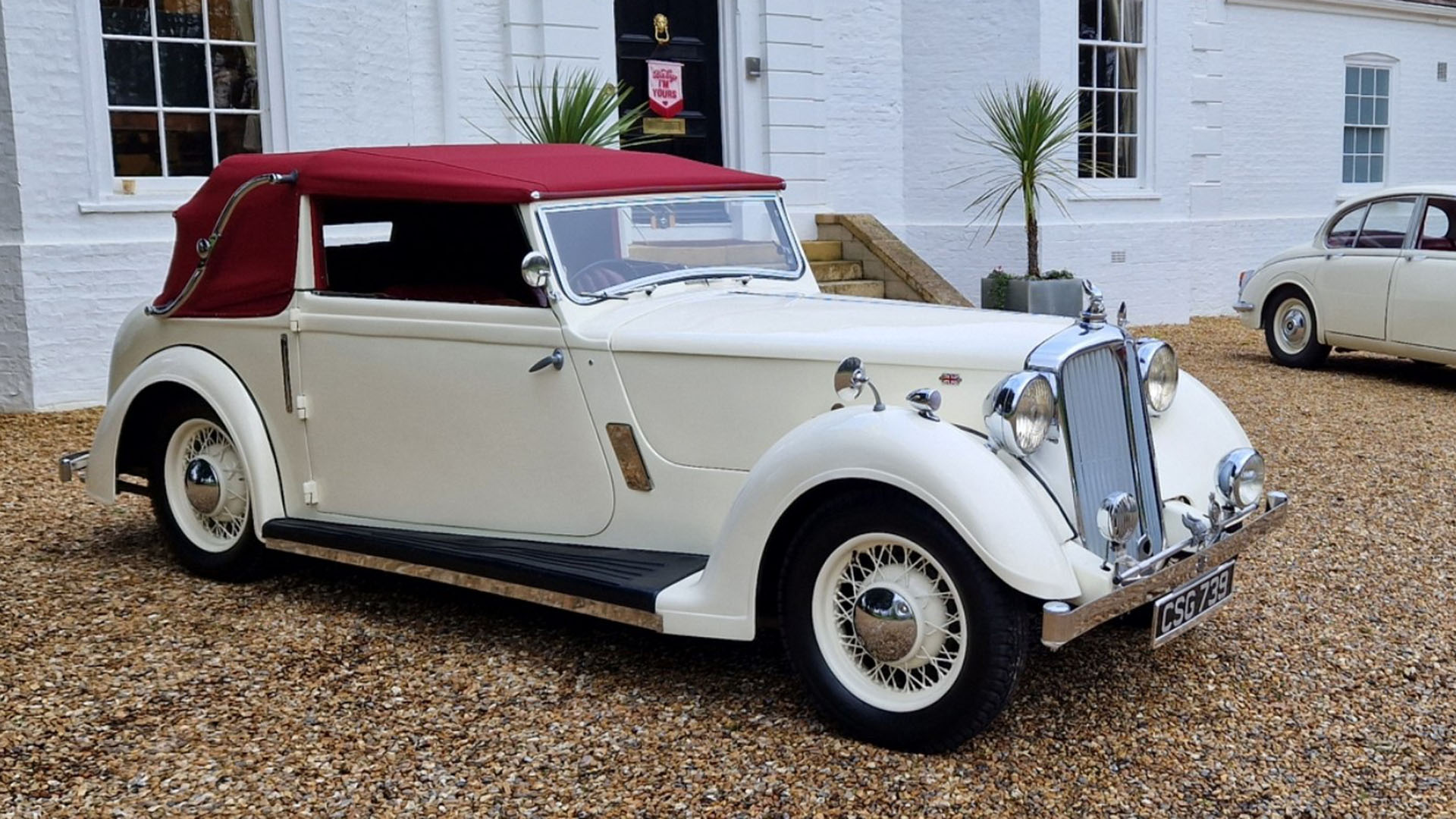 Right side view of a Ivory vintage Rover Tickford with burgundy soft top roof closed