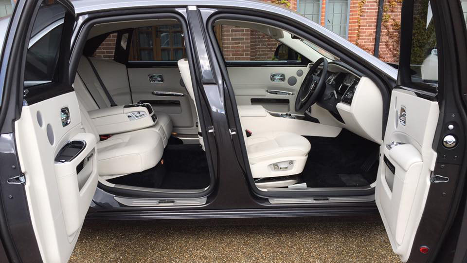 Right side view of a Rolls-Royce Ghost with both doors open showing white leather seats