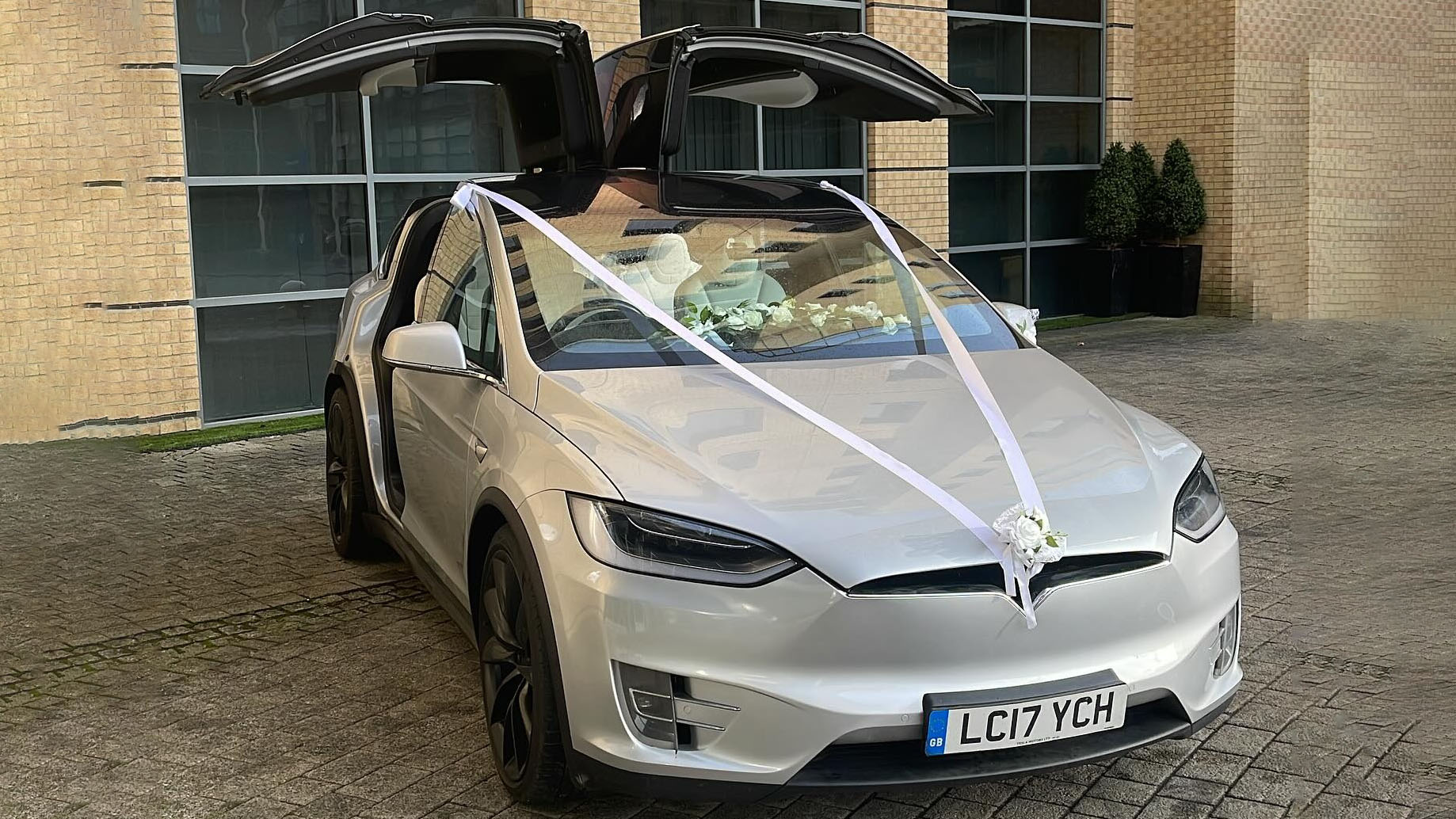 Silver Tesla X with Gull wings open and decorated with white ribbons