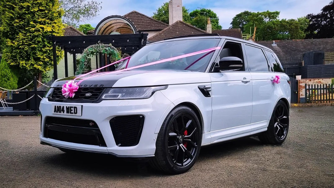 Front view of white Range Rover SVR with black alloy wheels and black carbon bonnet decorated with pink ribbons