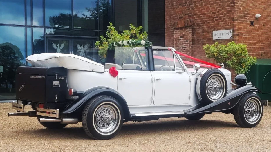 Right side view of white Beauford with convertible roof open and black picnic trunk at the rear