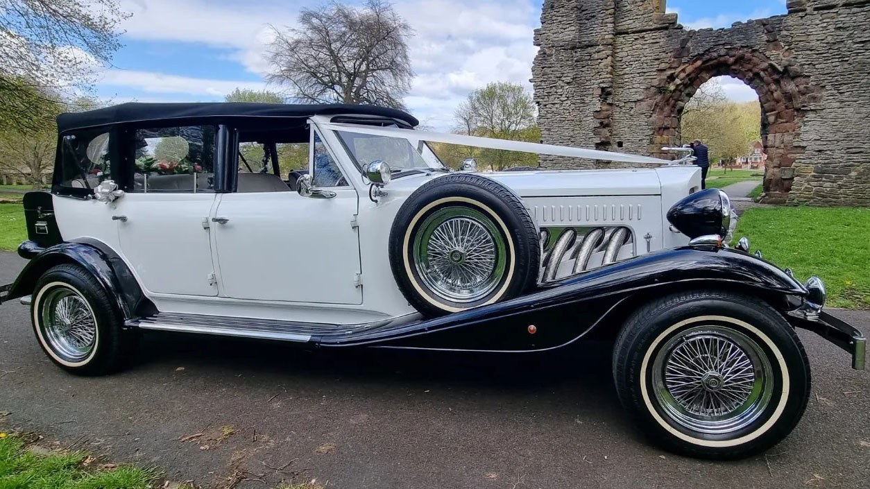 Right side view of a white Beauford with convertible roof open and spare wheel mounted on the side of the vehicle