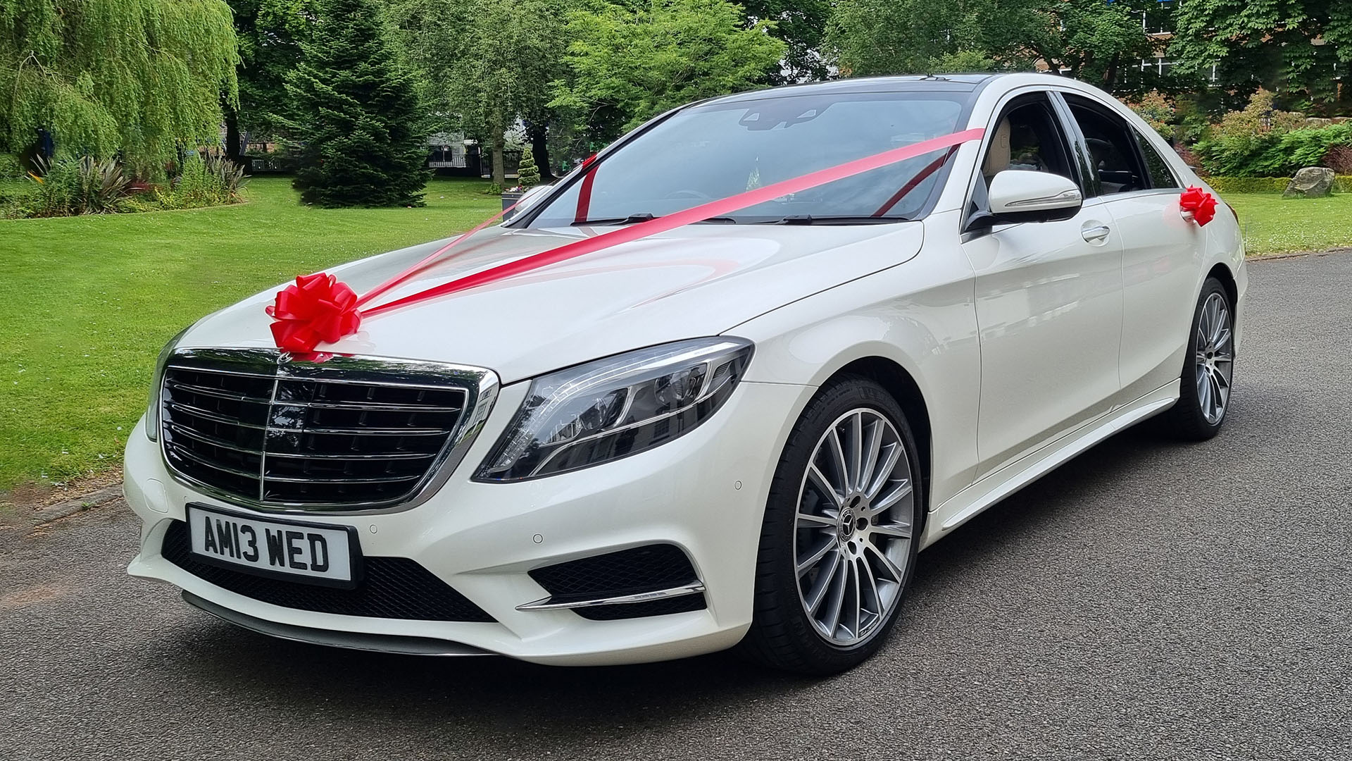 White Mercedes S-class at a wedding venue in West Midlands decorated with red ribbons and bows