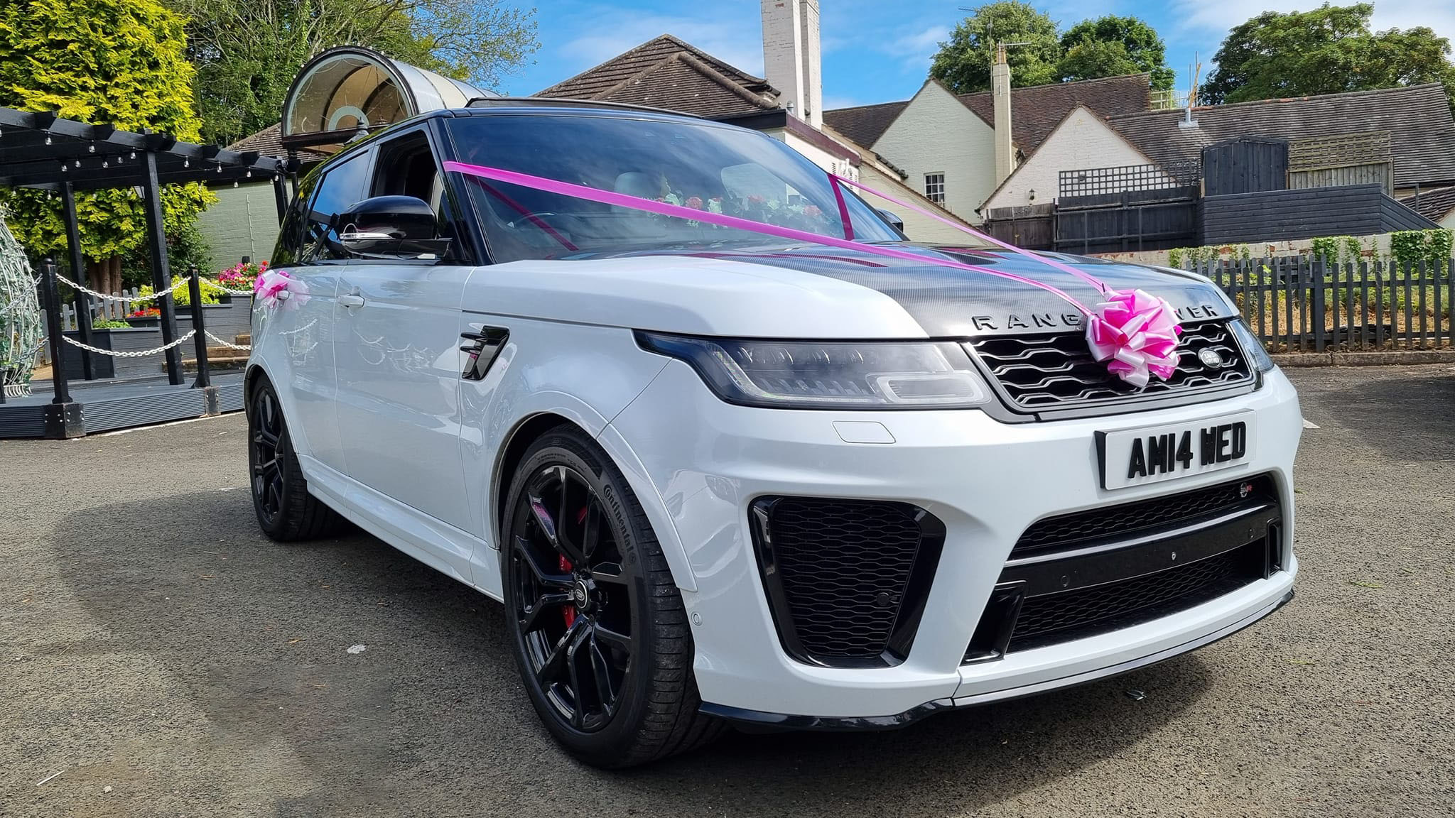 Front right view of white Range Rover with white and pink wedding ribbons and bows