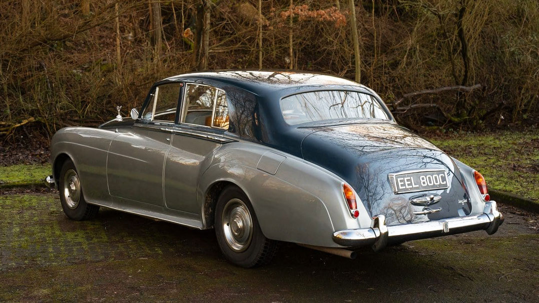 Left side rear view of two-tone blue and silver rolls-royce with chrome rear bumper