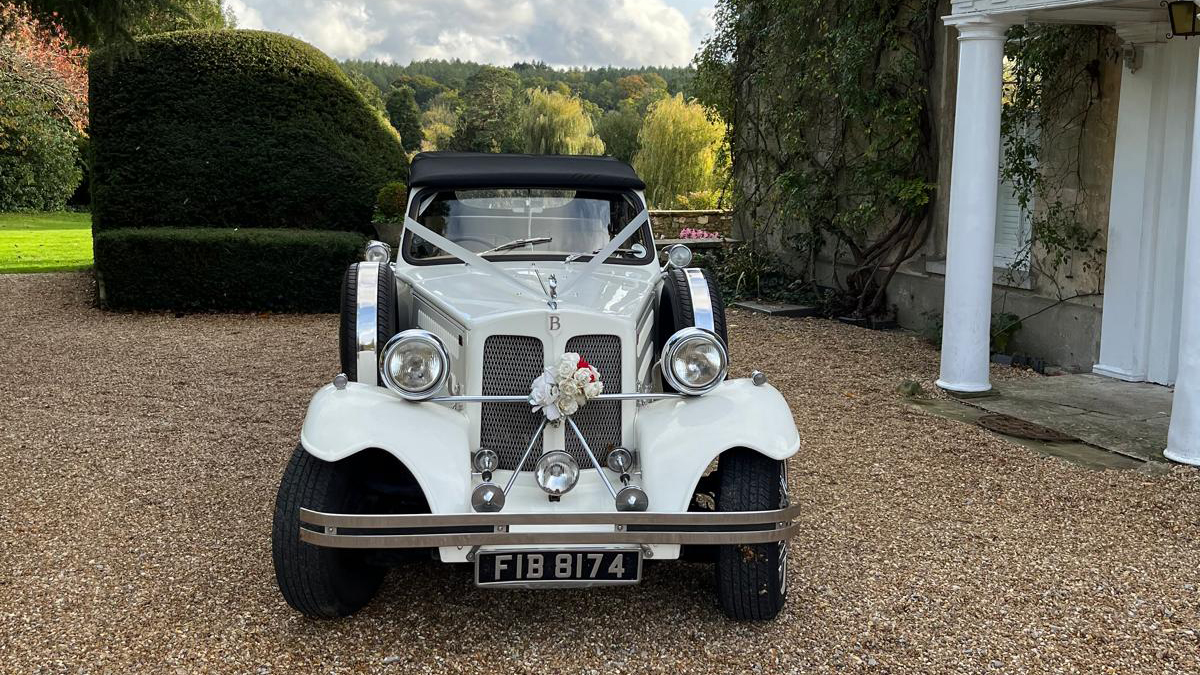 Full front view of Beauford Convertible with white ribbons across its bonnet and large white bow on front grill