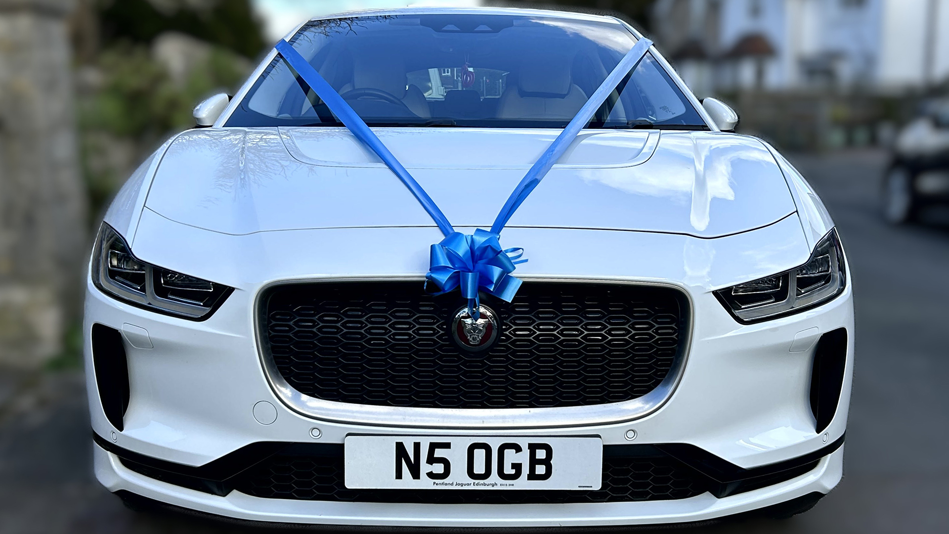 Front view of Jaguar I-Pace with blue ribbons and bows on its front grill