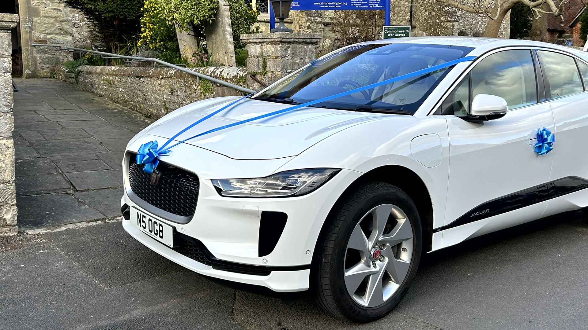 White Electric Jaguar I-Pace with blue ribbons and bows