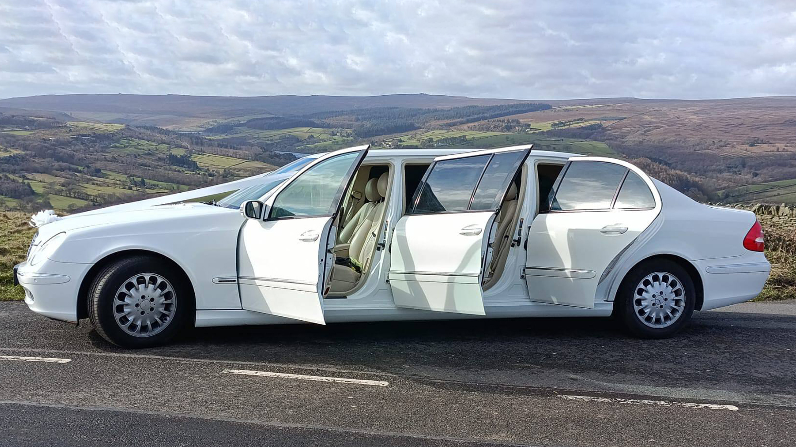 Left view of White Stretched Mercedes Limousine with doors open showing cream leather interior