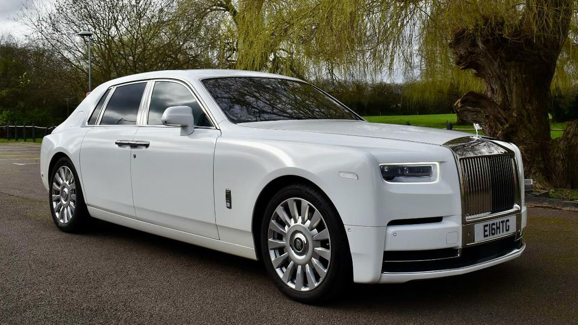 white Rolls-Royce phantom 8 EWB with chrome alloy wheels parked in underneath a tree