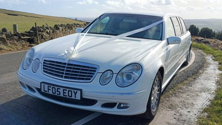 White Wedding Ribbons ons a White Stretched Mercedes Limousine front bonnet.