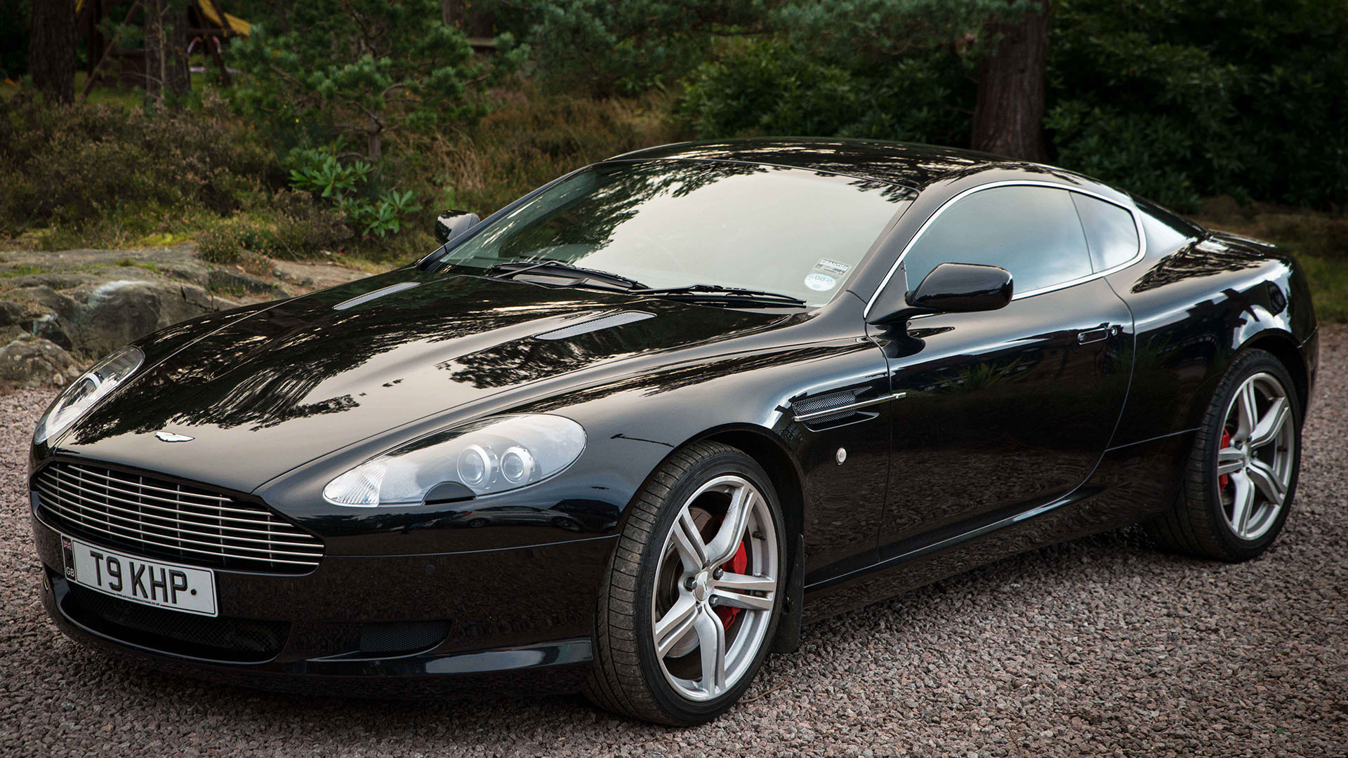 Front left side of Black Aston Martin DB9 with large alloy wheels