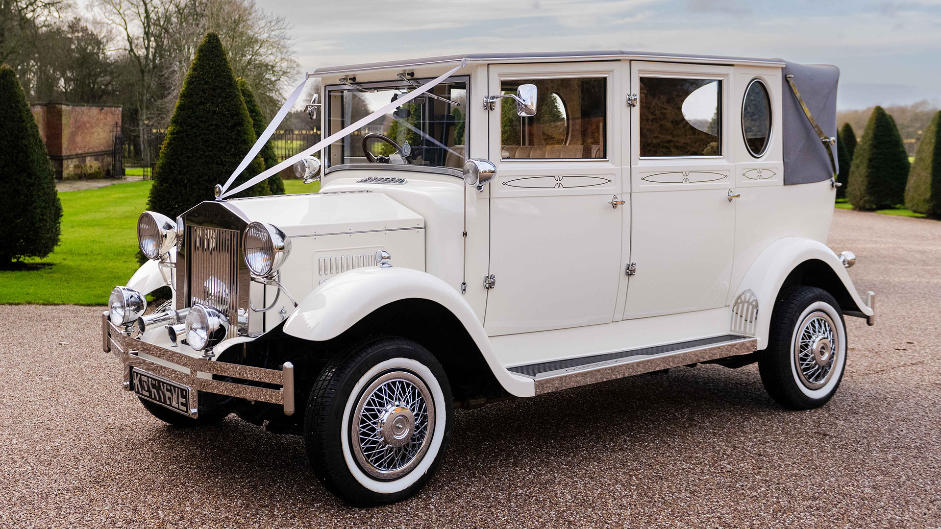 Old English White vintage Imperial wedding car with Grey Soft Top Retractable rear roof decorated with white wedding ribbons across the bonnet.