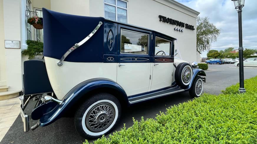 Rear right side of a blue and Ivory Vintage Imperial wedding car with semi-convertible blue soft top roof closed