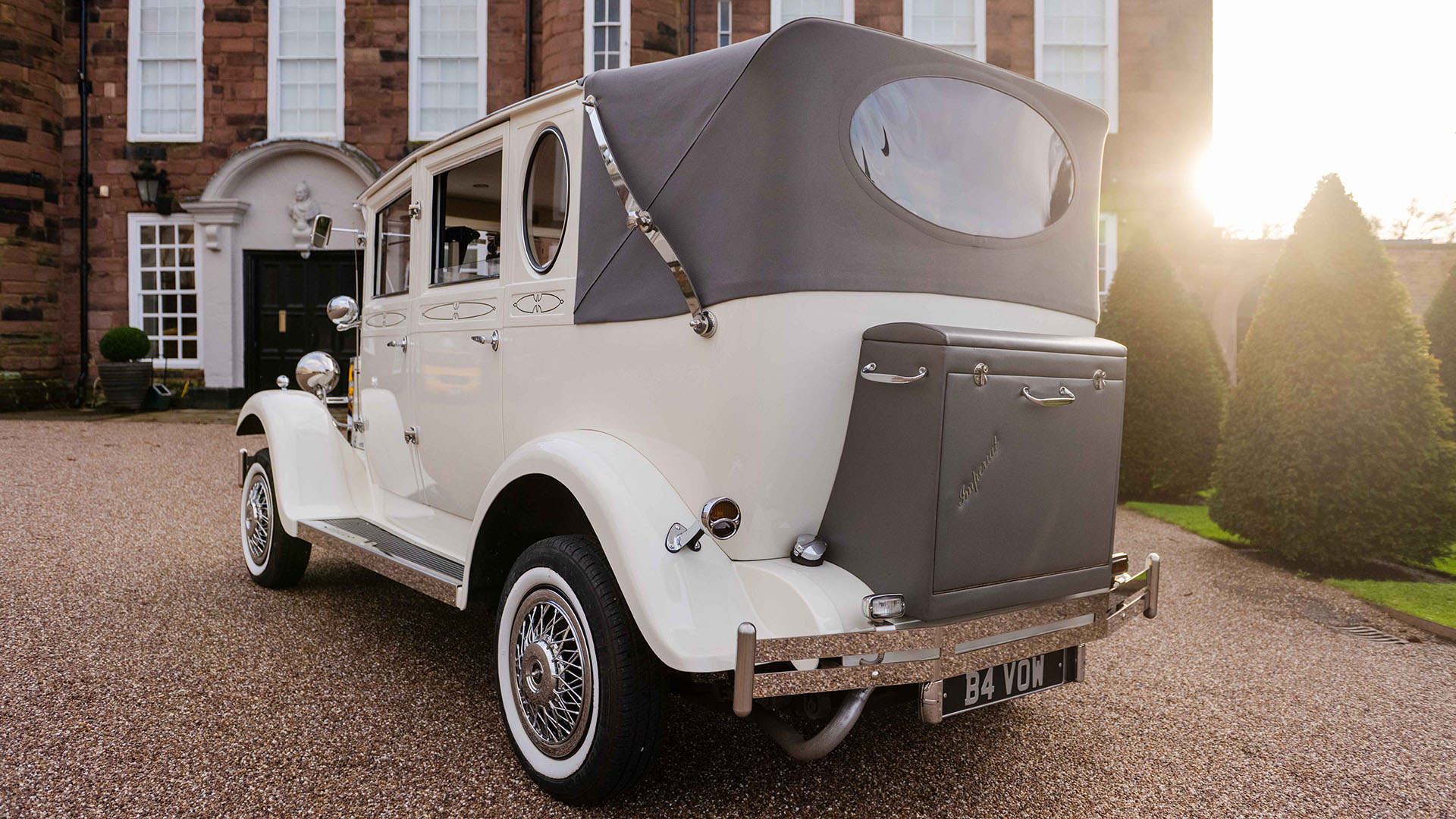 Rear view of Cream Imperial wedding car with grey soft top convertible roof and grey picnic trunk at the rear