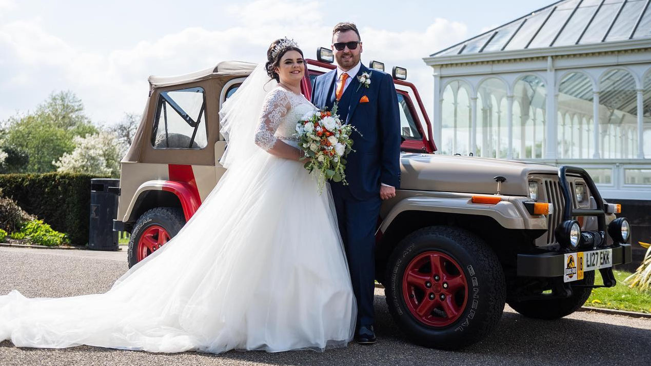 Bride and groom standing in front of Classic Jeep Wrangler from the Jurassic Park movie