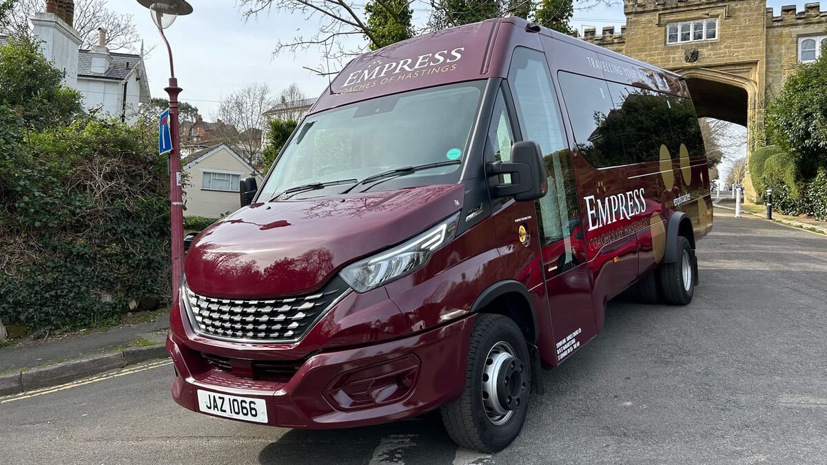 Front view of a burgundy Modern 22-seater Coach parked at wedding venue in Hastings, Sussex