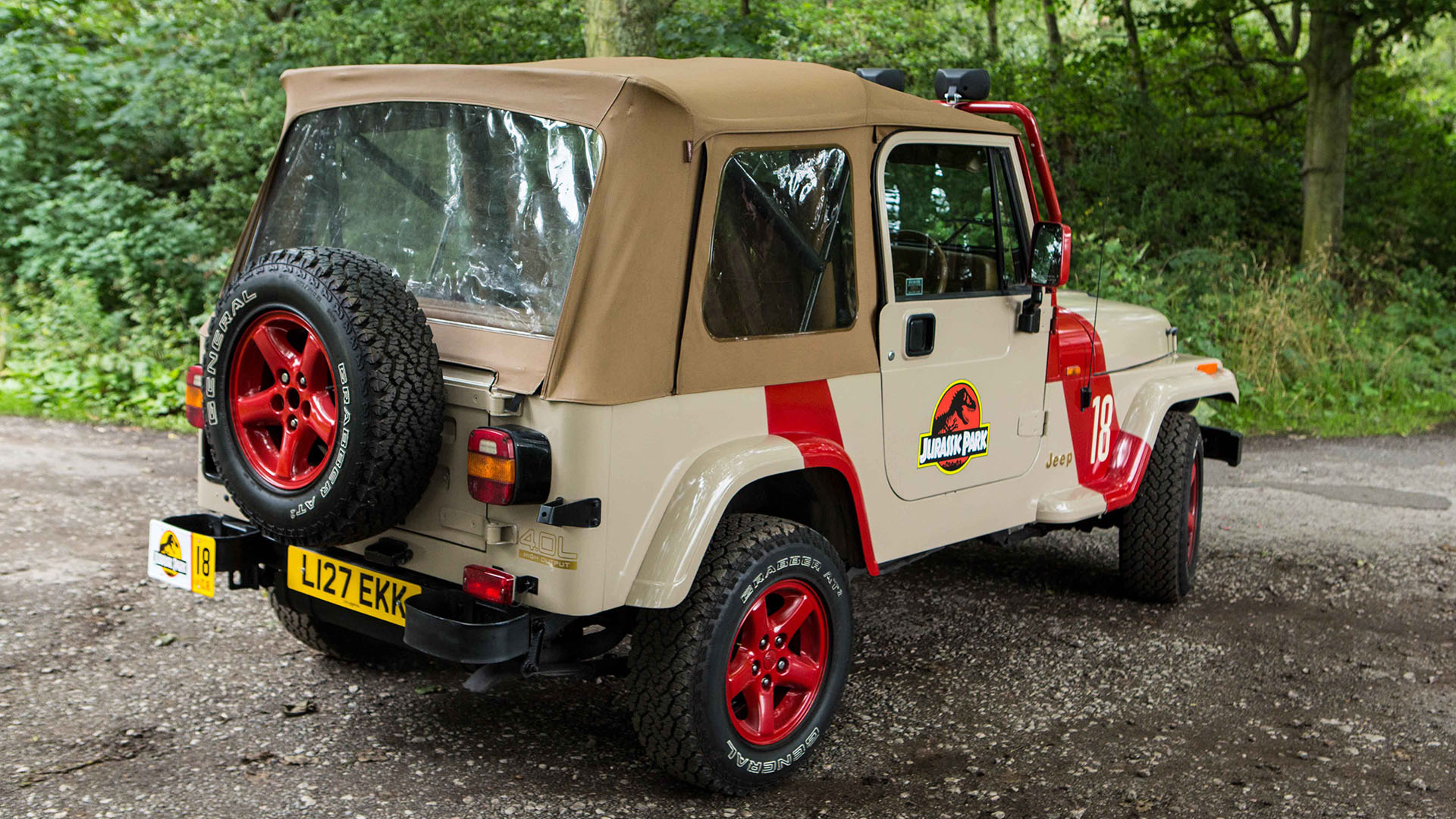 Rear view Jeep Wrangler with beige canvas roof closed, spare wheel mounted at the rear of the vehicle