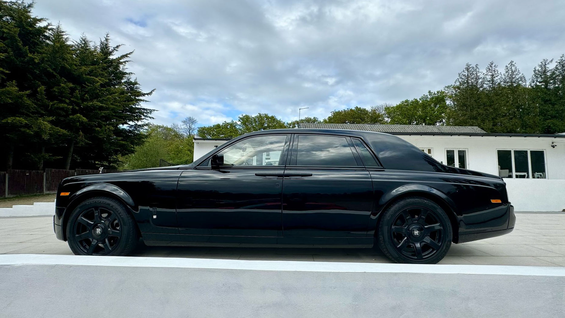 Black Rolls-Royce Phantom left side view showing black alloy wheels and privacy rear windows