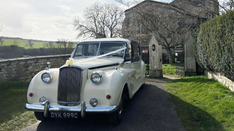 Frotn view of Classic Austin Prioncess with chrome grill and pink wedding ribbons in front of the vehicle