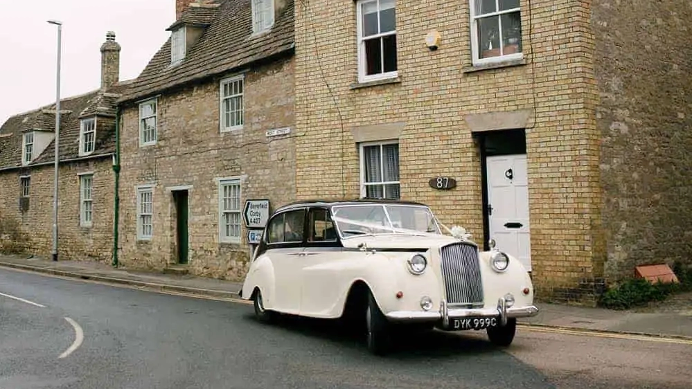 Classic Austin Princess parked in front of a wedding venue in Leicester decorated with wedding ribbons